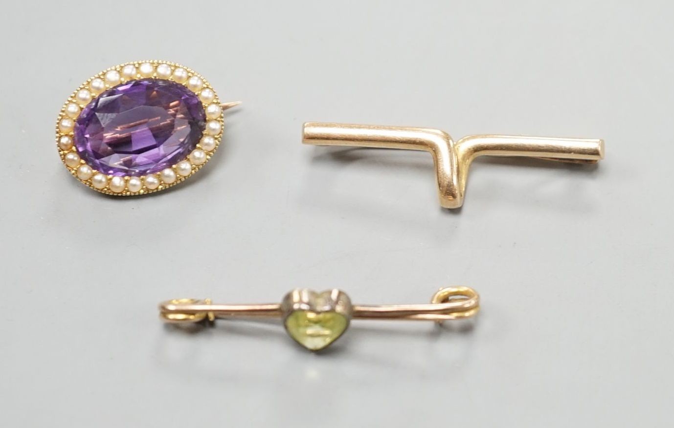 A yellow metal cravat pin, 37mm, a 9ct and heart shaped gem set bar brooch and a yellow metal, amethyst and seed pearl set oval brooch, gross weight 10.4 grams.